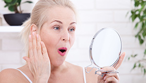 Woman looking at wrinkles in mirror
