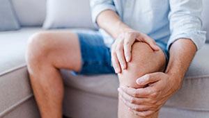 Close-up of person on couch rubbing their knee