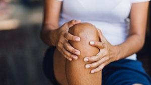 Close-up of woman in blue shorts holding her knee