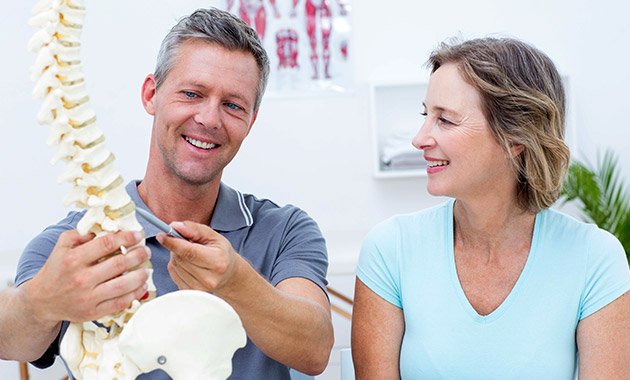 Patient and chiropractor looking at spinal model