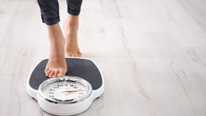 woman stepping on scale after medical weight loss in Richardson