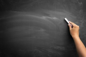 hand with chalk writing on a blackboard