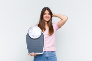 woman who has unintentionally gained weight holding a scale