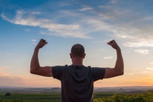 man flexing his arms after getting testosterone hormone therapy