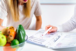 nutritionist working with a patient with a bowl of food on the table